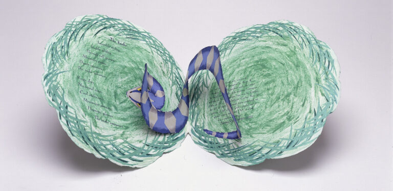 A paper art sculpture shows a curled blue and white striped snake on top of two green, textured, nest-like circular shapes, against a plain white background.