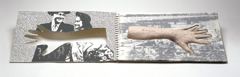 A book laid open with a light-skinned paper cast forearm in the middle of the righthand page which is a black-and-white photo of barracks. “B-11226” is written on the arm, resembling a tattoo. On the left page, there is a cutout in the shape of the arm overlapping a black-and-white image of a man and woman smiling at each other.