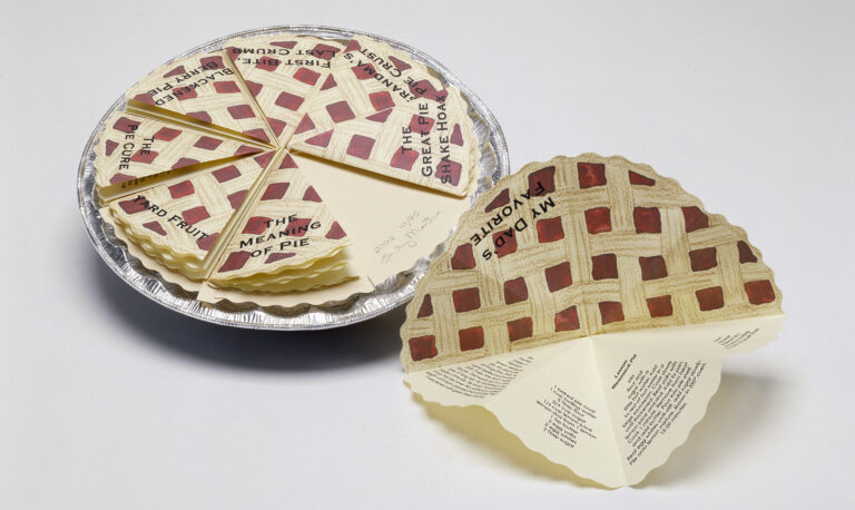 A pie tin filled with eight small folded pieces of paper that resemble identical slices of pie with a lattice top and red filling. Each slice is labeled with a title in black and opens, containing short stories written inside.