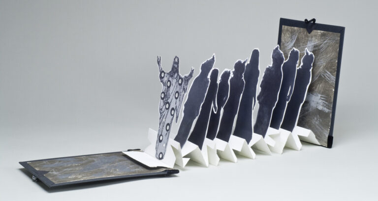 Accordion-style book with black and white cutout human silhouettes standing upright, partially unfolded, with abstract designs on the figures and a textured, dark cover at either end. Set against a plain light background.