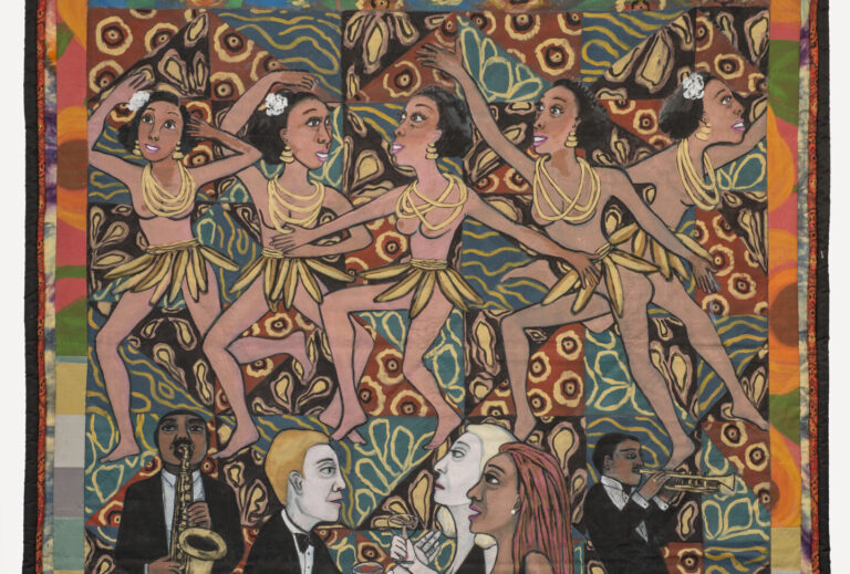 Colorful quilt with a multi-patterned background that depicts five medium skin toned, bare breasted dancing women wearing skirts of bananas and yellow necklaces. Below, from left to right, a medium-dark skin toned and light skin toned men and women interact and play brass instruments.