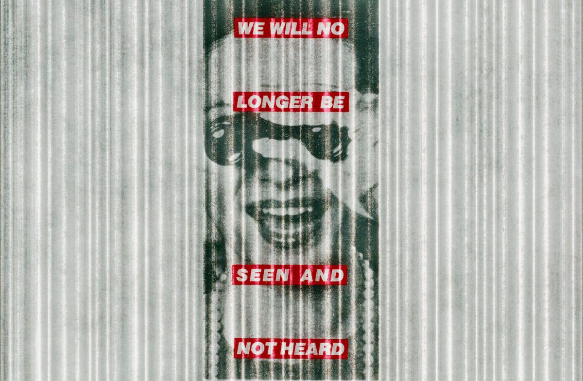 A black-and-white image of a light-skinned woman is centered atop a grey-and-white vertically striped background. She wears pearls and holds a pair of binoculars to her eyes while smiling widely. Superimposed over the image are four red horizontal bands with the phrase 'We will no longer be seen and not heard' in white block letters.