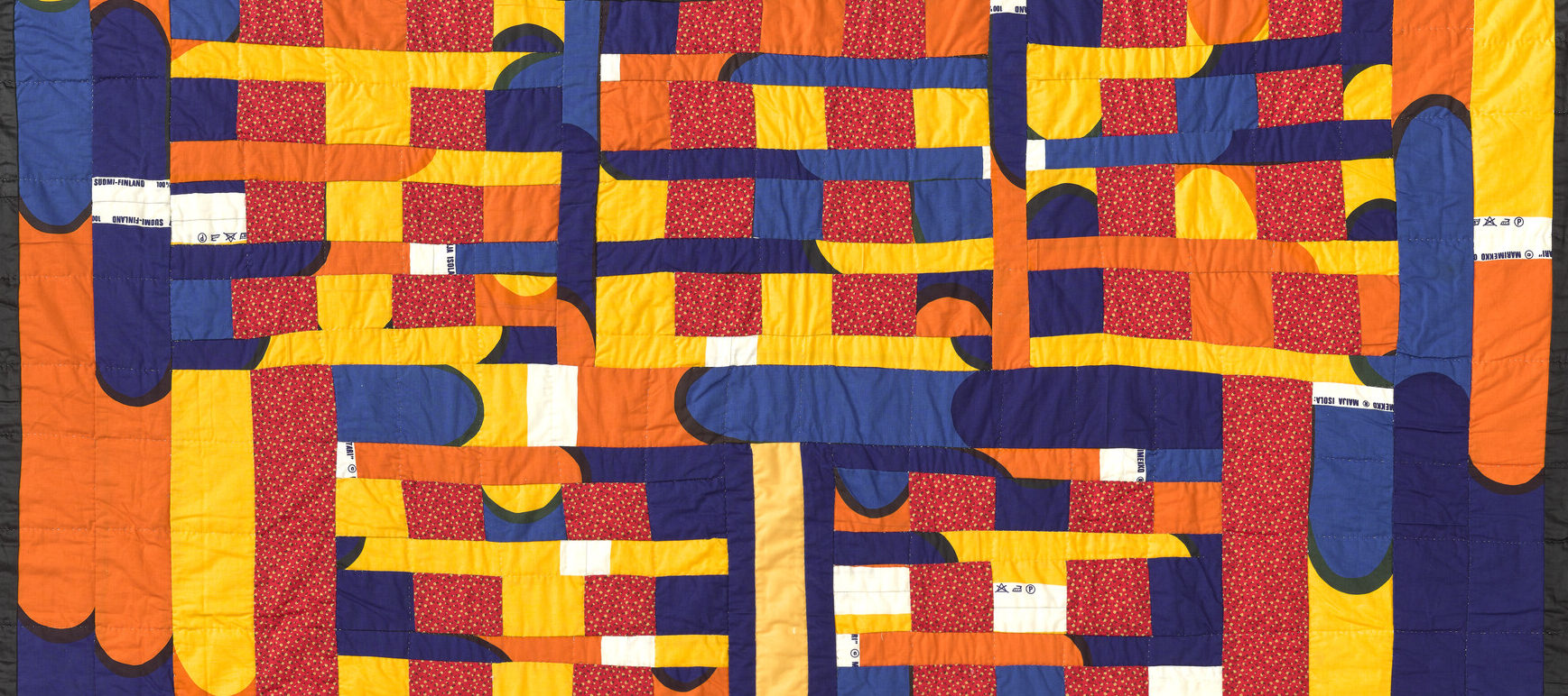 A vibrant, hand-quilted cotton textile features a combination of blue, orange, yellow, and red patchwork.
