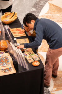 A man and a boy look at various art prints on a black table.