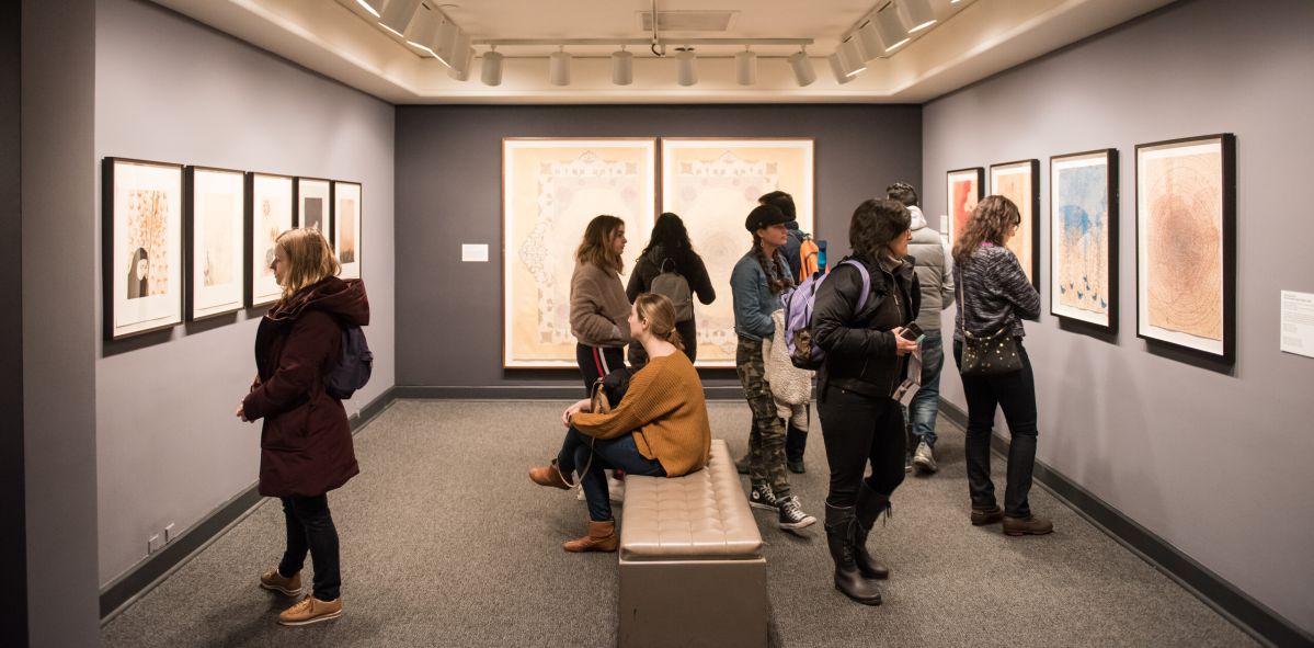 Museum visitors are gathering in a small gallery space.