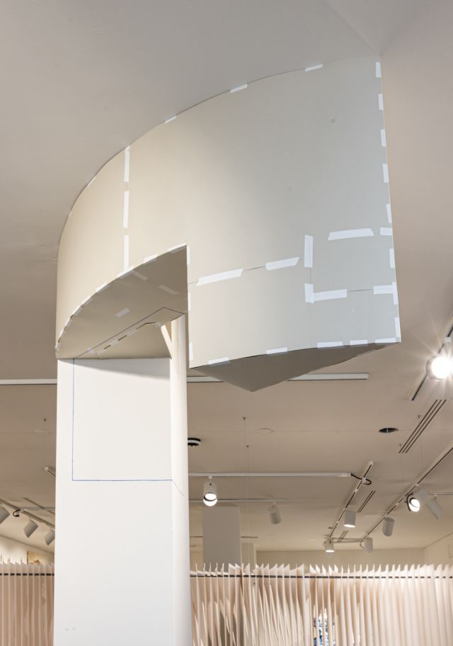 Beige paper geometric construction anchored to the ceiling and white square column