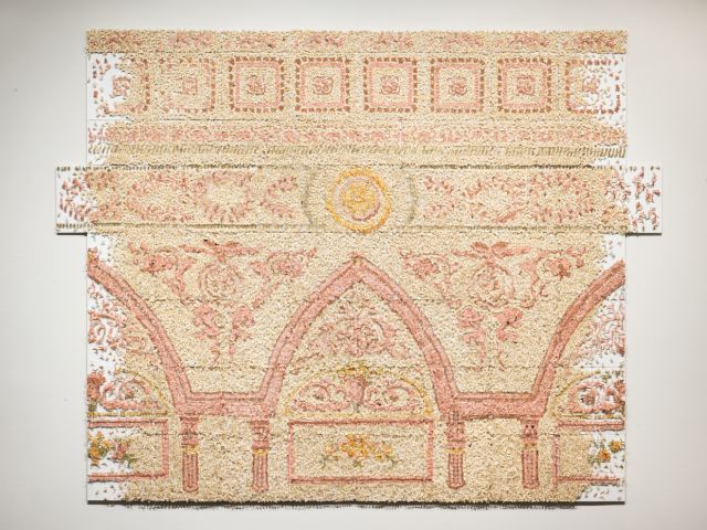 A large contemporary art installation of a decorative architectural cornice made of countless pink and yellow cut paper insects.