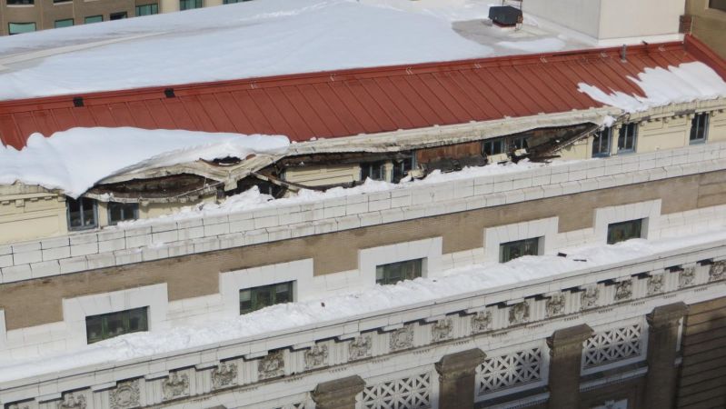 Close-up of museum's exterior roof showing damage to the gutters caused by heavy snow that is also present in the photograph.