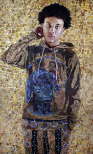 A mosaic style painting of a young brown skinned boy with black curly hair, who stands facing the viewer. He is wearing a brown hoodie sweatshirt, with the image of a parent holding their child on it. He and the background behind him is created from an elaborate layered mosaic of largely golden and brown hued square tiles.