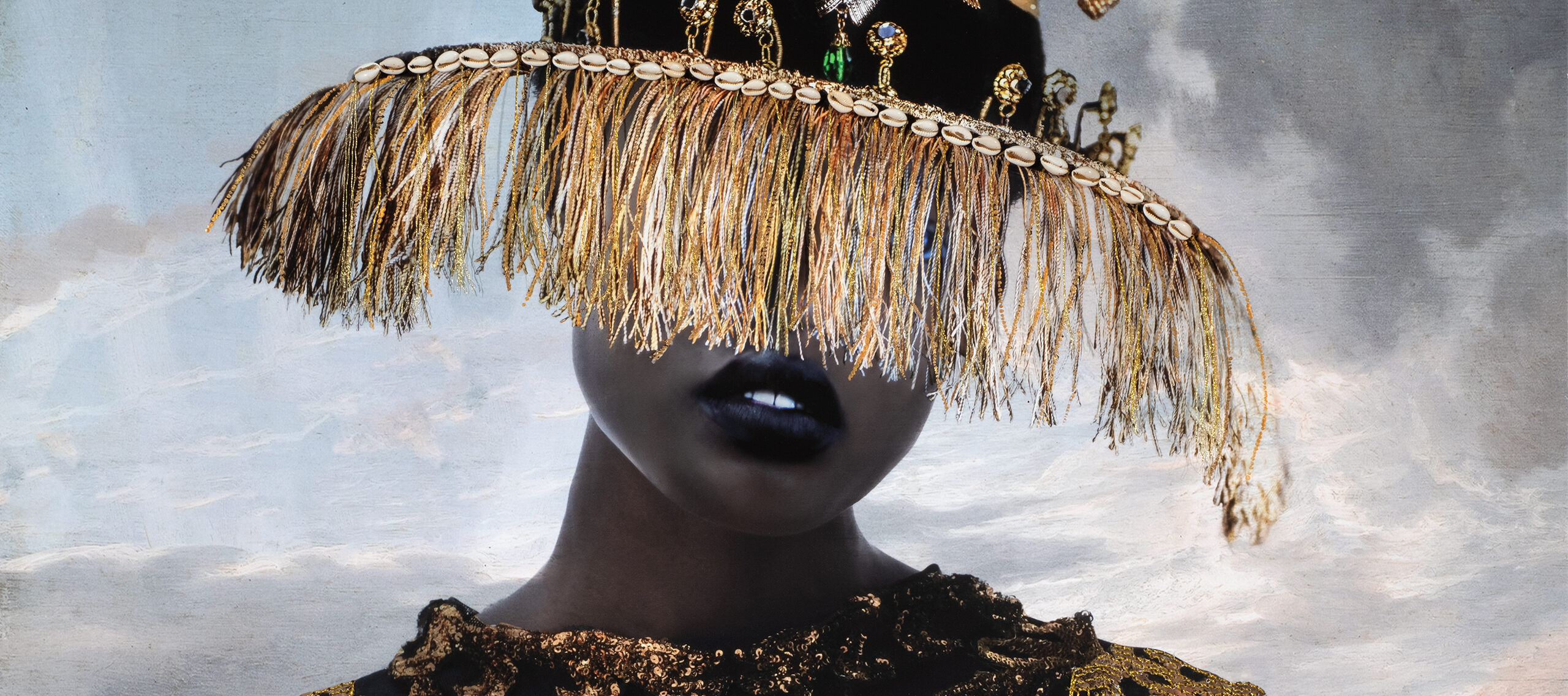 A person with dark skin tone in a black-and-gold ornate dress with gold chain details wears a wide-brimmed hat decorated with gold fringe and plants, obscuring their eyes. The background shows a cloudy sky.