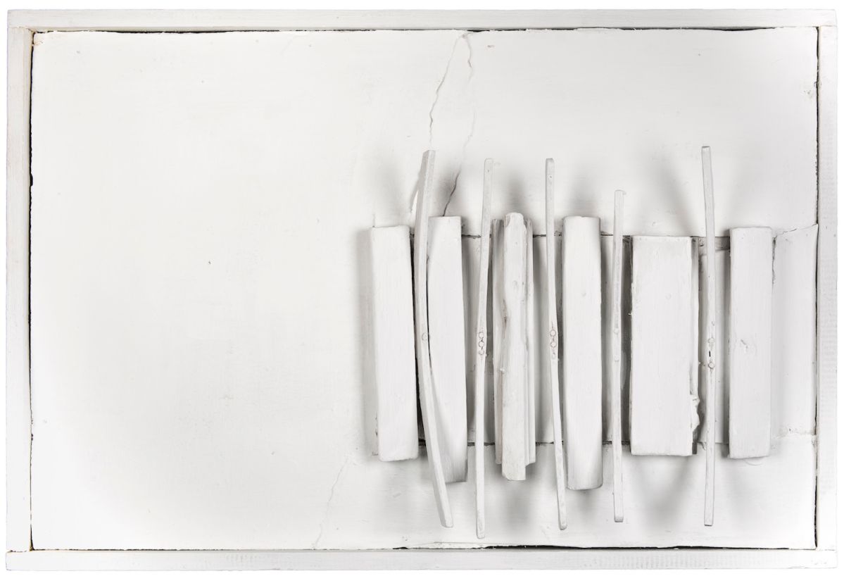 Multiple rectangular wooden shapes and dowels positioned vertically and casting shadows on the right side of a whitewashed wooden canvas.