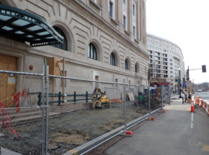 A construction fence and equipment in front of the building facade.